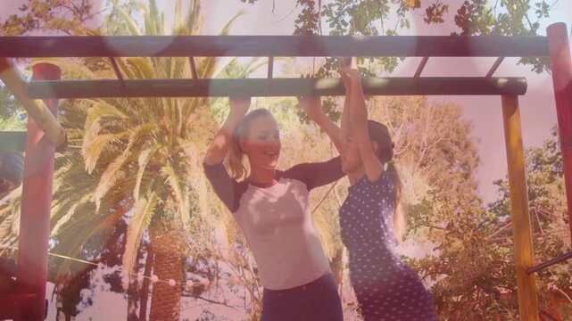 Child reaching up, pregnant woman supporting child, girl hanging from monkey bars for health