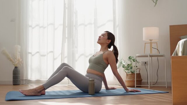 Healthy Asian woman relaxing after home yoga session on mat