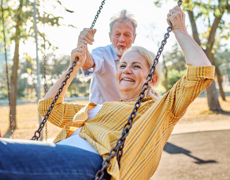 Happy active senior woman having fun on a swing in park outdoors