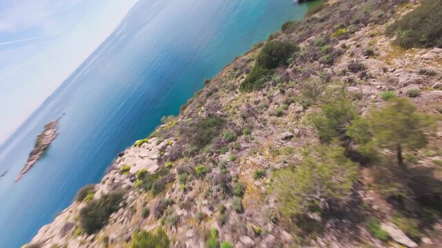 Dynamic FPV drone flight over a field of yellow flowers transitioning into rocky coastal cliffs with a scenic lighthouse reveal at the end