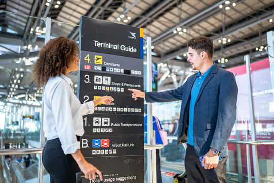 Travelers consult terminal guide sign for directions at modern airport terminal