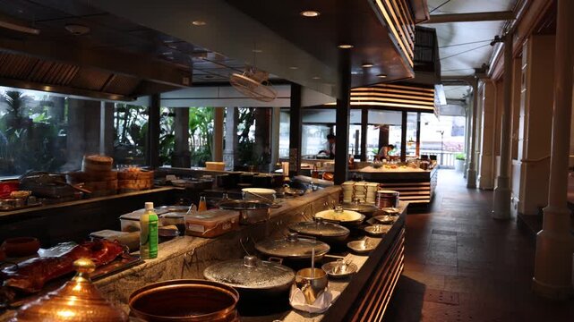 Luxury hotel breakfast buffet area with variety of hot dishes and gourmet cuisine at sunrise.