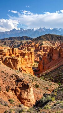 A scenic vista of a vibrant red canyon, with towering rock formations and majestic snow-capped mountains in the background