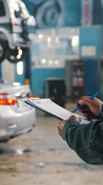 Mechanic writing car service checklist in auto repair shop