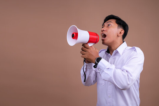 Side View of an Asian Man in White Uniform Shouting Into Red Megaphone