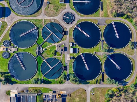 Aerial view of circular water treatment tanks contrasting with the surrounding green landscape, Sausheim, Grand Est, France.