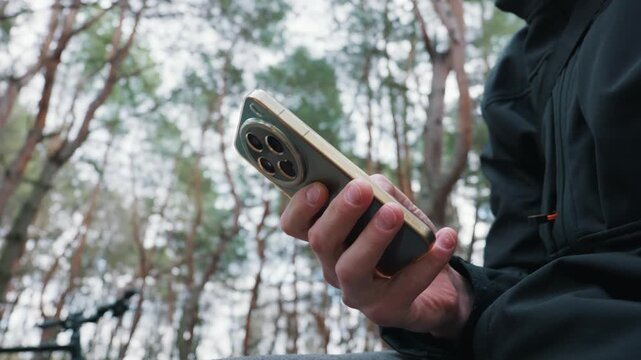 A man hand holds a gold and green smartphone featuring a large circular camera module. This represents modern connectivity and the intersection of technology and nature.