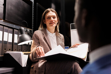 Woman police officer explaining criminal case to african american detective, working at federal...