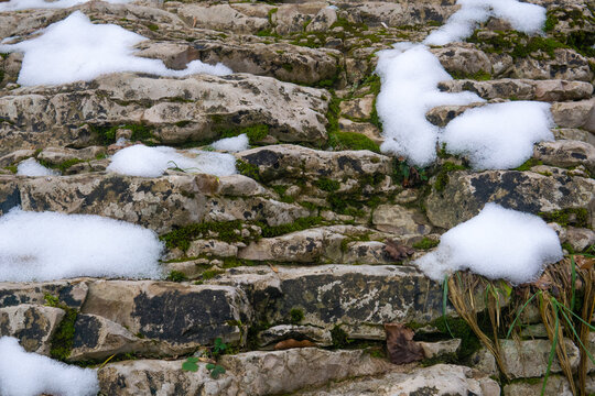 Stone wall covered with snow. Winter landscape with snow and ice.