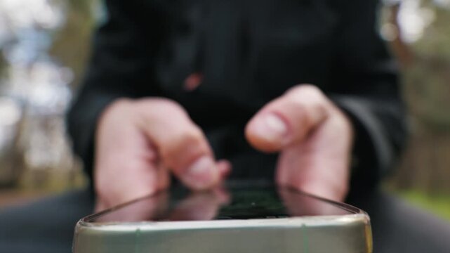 Hands of an individual hold a mobile device while typing and scrolling on the touchscreen with a shallow depth of field. Digital connectivity serves as the visual concept.
