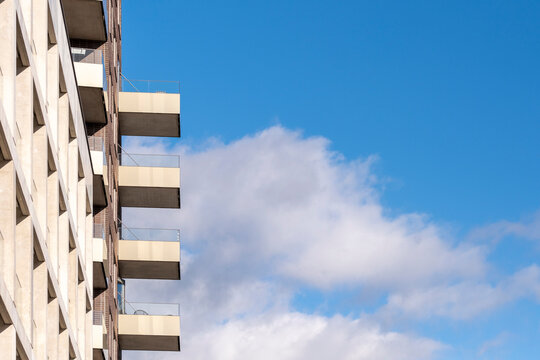 Minimal modern architecture building facade skyline cityscape showing concrete balcony modules and repeating rectangles under sky clouds background in quiet city context
