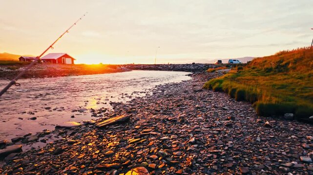 Kokelv, Hammerfest, Finnmark, Norway - The Sun Sets Behind a Red Cabin, Casting a Warm Glow Over the Rocky Shoreline and Fishing Pole - POV Shot