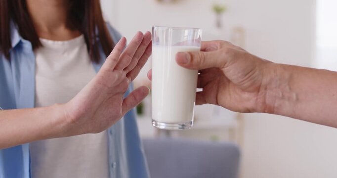 Lactose intolerance and cow milk allergy as causes of stomach pain and cramps, nausea and gut discomfort in woman. Female hand rejecting glass of dairy product at home to avoid intolerant trigger