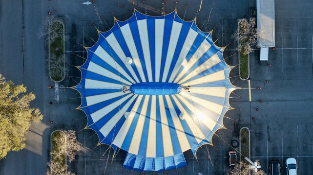 Aerial view of a striking blue and white striped circus tent standing boldly in a stark parking lot, St. Augustine, Florida, United States.