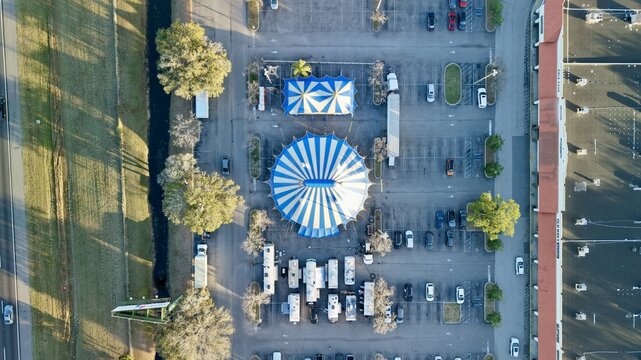 Aerial view of the circus tents with blue and white stripes surrounded by parked cars and RVs, creating a vibrant scene, St. Augustine, Florida, United States.