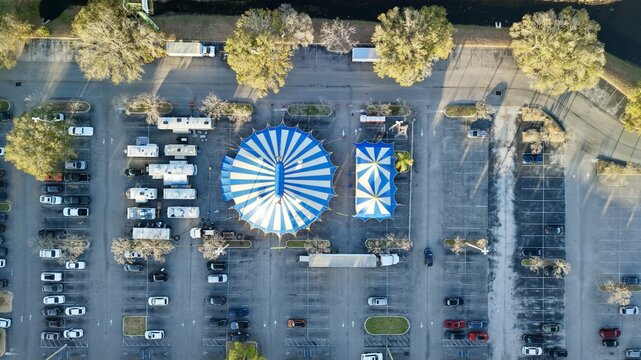 Aerial view of a vibrant blue and white striped tent and a smaller tent nestled in a parking lot near the St. Augustine Amphitheatre, St. Augustine, Florida, United States.
