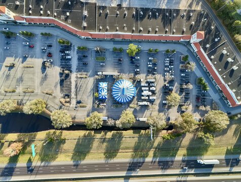 Aerial view of a blue and white striped circus tent pitched near a busy highway and a vast parking lot surrounded by buildings, St. Augustine, Florida, United States.