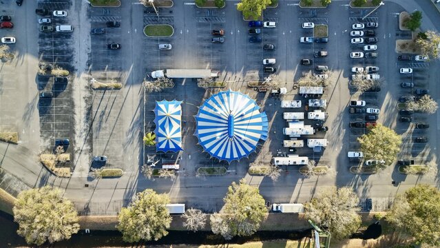 Aerial view of a blue and white striped circus tent standing out in a parking lot surrounded by vehicles, St. Augustine, Florida, United States.