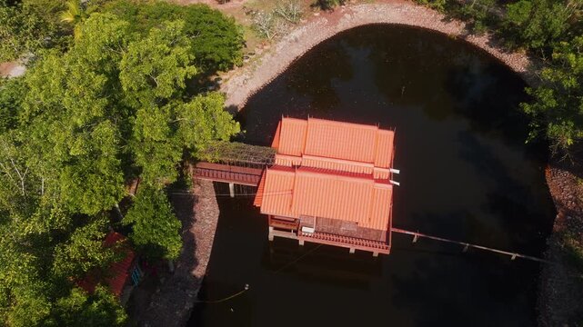 Drone rises above house on water surrounded by tropical forest in Rayong