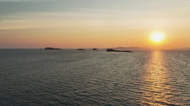 Drone flies over ocean toward islands with sunset light in Rayong Thailand