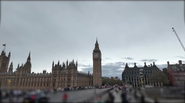 People and traffic moving quickly on westminster bridge near big ben and the houses of parliament in london, uk on a cloudy day with a special lens effect