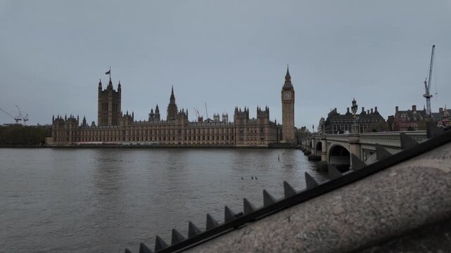 Iconic palace of westminster and big ben tower standing on the bank of the river thames with westminster bridge on a moody, overcast day in london, united kingdom