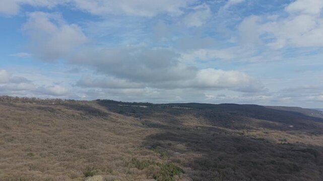 Aerial drone footage showing rolling terrain under cloudy sky with expansive natural landscape
