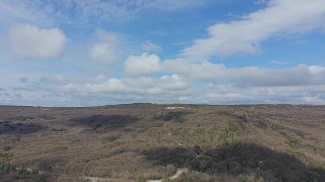 Drone panorama of rolling hills beneath cloudy sky with natural scenery and distant horizon