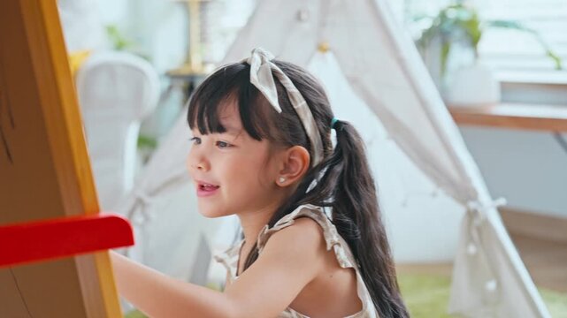 Little Asian girl drawing on a canvas enjoying creative time