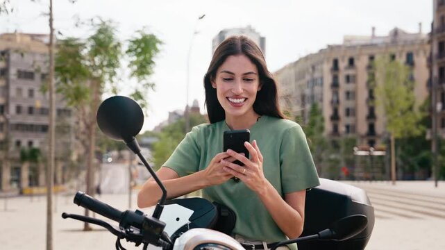 Video of beautiful woman taking selfies with smartphone while stopped on a motorbike in the city