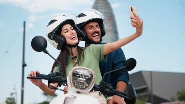 Video of cute couple taking selfies with smartphone while stopped on a motorbike in the city