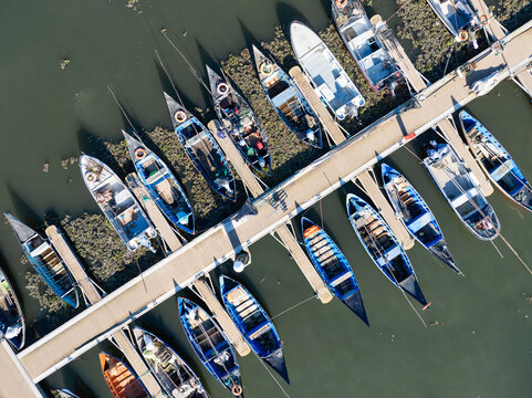 Aerial view of boats docked at Porta de Abrigo da Torreira, their vibrant colors contrasting with the dark water, Porta de Abrigo da Torreira, Aveiro, Portugal.