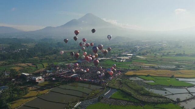 Hot air balloons float over a quaint village by mount sindoro in indonesia. Ideal for travel blogs, tourism promotions, and adventurethemed content.