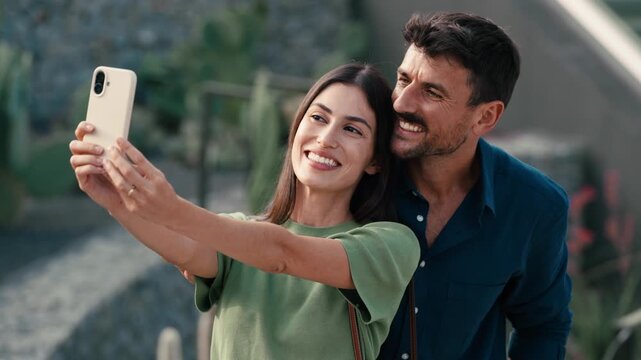 Video of beautiful couple taking photos of themselves with smartphone in the city