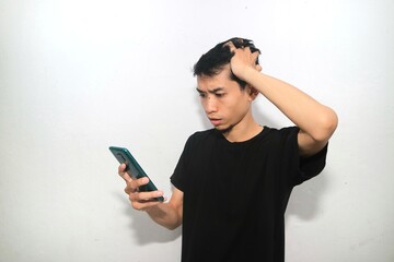 Fototapeta premium An Asian man wearing black shirt showing shocked expression when looking to his mobile phone