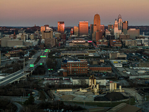 Aerial view of Cincinnati's skyline ablaze with the warm hues of sunset, casting long shadows over the cityscape and the Ohio River, Cincinnati, Ohio, United States.