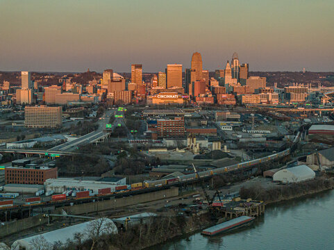 Aerial view of a city skyline bathed in the warm glow of the setting sun, highlighting the contrasting textures of buildings and the river, Cincinnati, Ohio, United States.