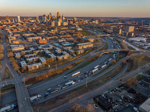 Aerial view of a bustling city where the highway weaves through buildings under the soft glow of the setting sun, Kansas City, USA.