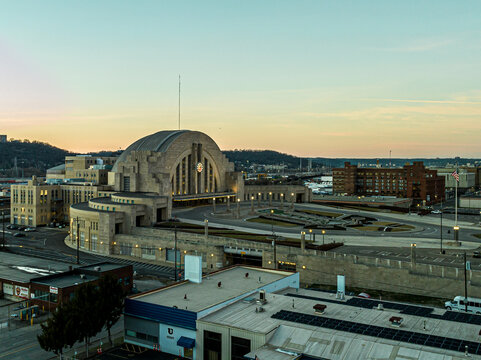 Aerial view of the iconic Cincinnati Union Terminal stands majestically against the soft hues of the setting sun, its art deco facade glowing warmly, Cincinnati, Ohio, United States.