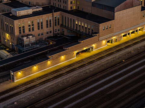 Aerial view of the illuminated platforms and tracks of Union Terminal, casting a warm glow against the cool shadows of the surrounding architecture, Cincinnati, Ohio, United States.