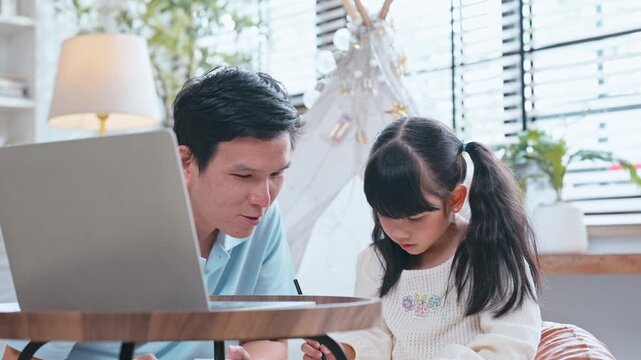 Asian family father, mother, and young daughter sitting on sofa and looking at digital tablet for education or entertainment