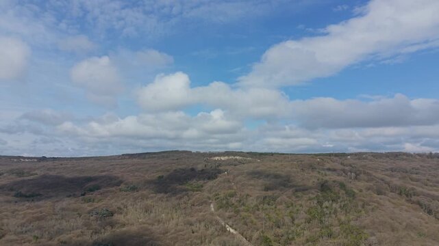 Drone panorama of rolling hills beneath cloudy sky with natural scenery and distant horizon