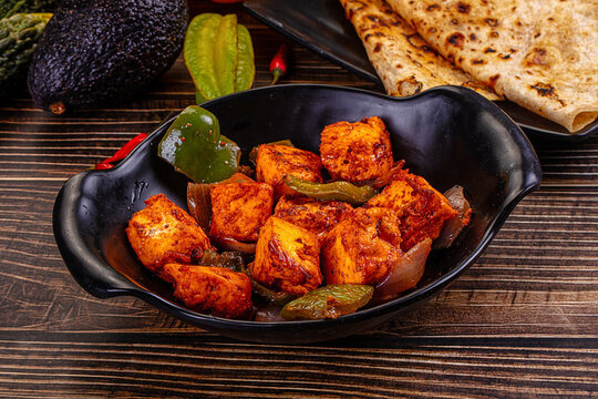 Indian Paneer Tikka Masala inl with Roti bread on a dark wooden table