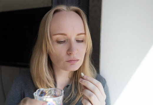 Woman taking iron supplement capsule with glass of water. Female health care, iron deficiency anemia treatment, vitamins and minerals intake for wellness.