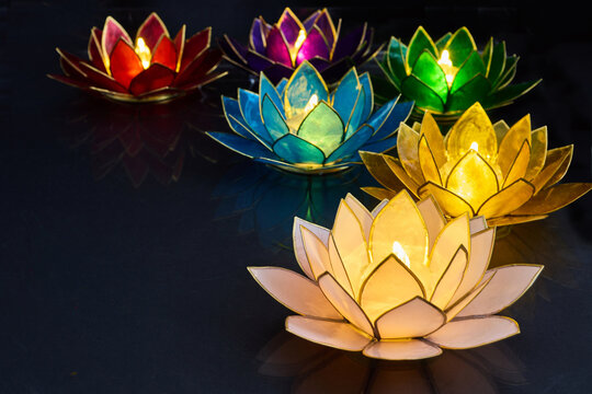 Vesak day. Colorful glowing lotus flower candle holders floating