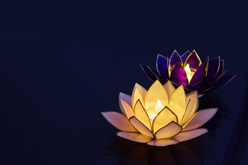 Naklejka premium Vesak day. Floating lotus candle lanterns illuminating dark water at night