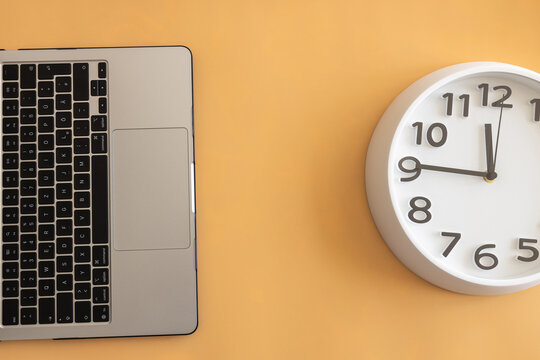 Laptop and wall clock on a beige background, symbolizing productivity, time management, remote work and modern workspace organization.