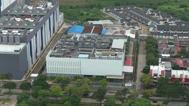 Aerial view of a modern data center complex with cooling systems on the roof, located in an urban area of jakarta, indonesia