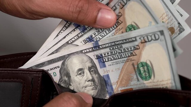 US Dollar money or currency in male hands counting close up. Male hands counting American 100 USD banknote from a wallet or purse. Financial concept.