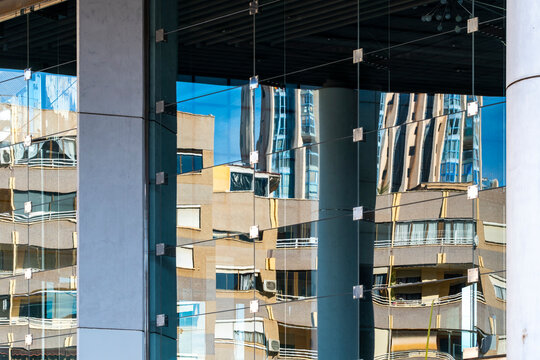 Columns behind glass facade reflection on modern urban architecture showing building pattern and contrast with structured depth